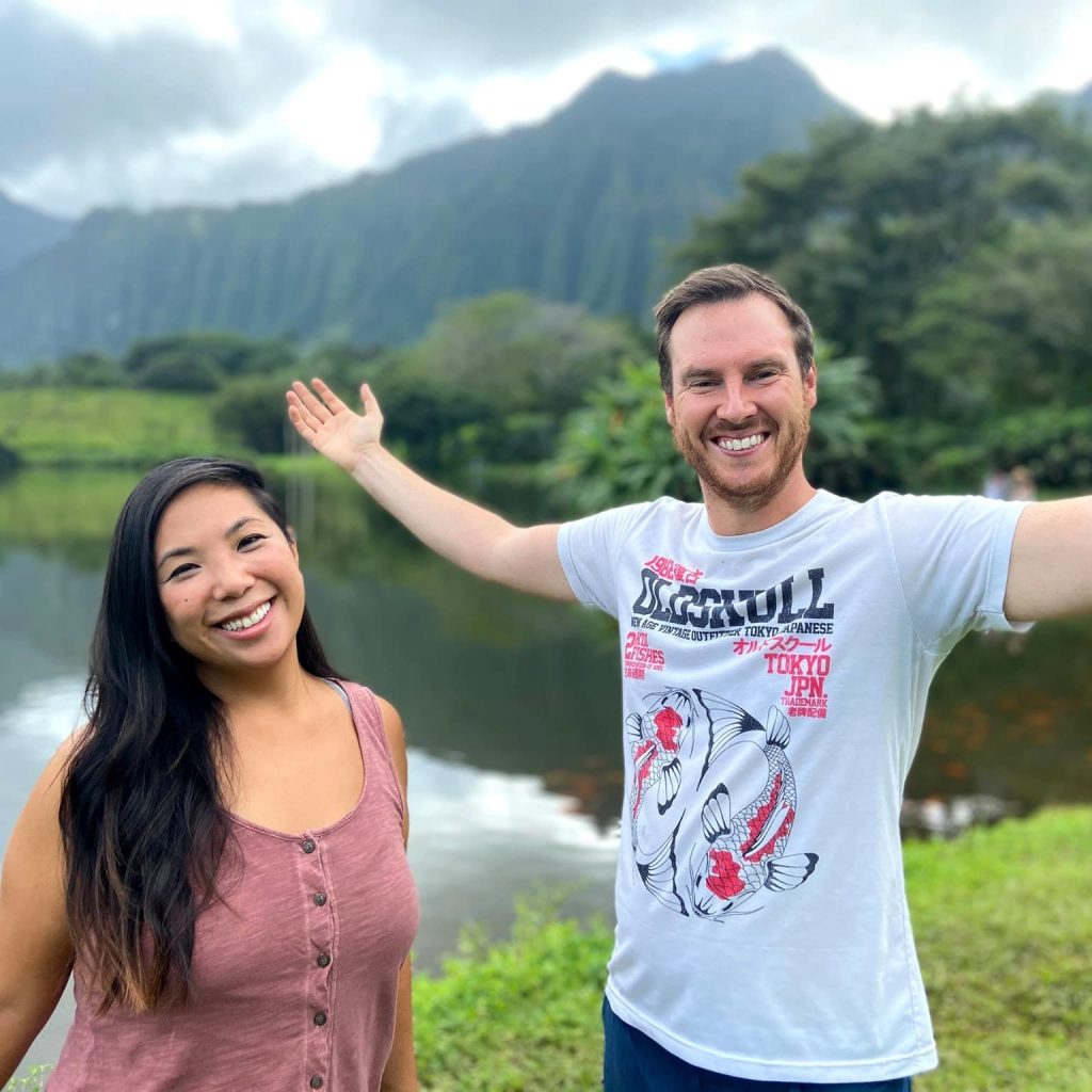 Lisa & Josh | Two people standing in front of a lake with mountains in the background.