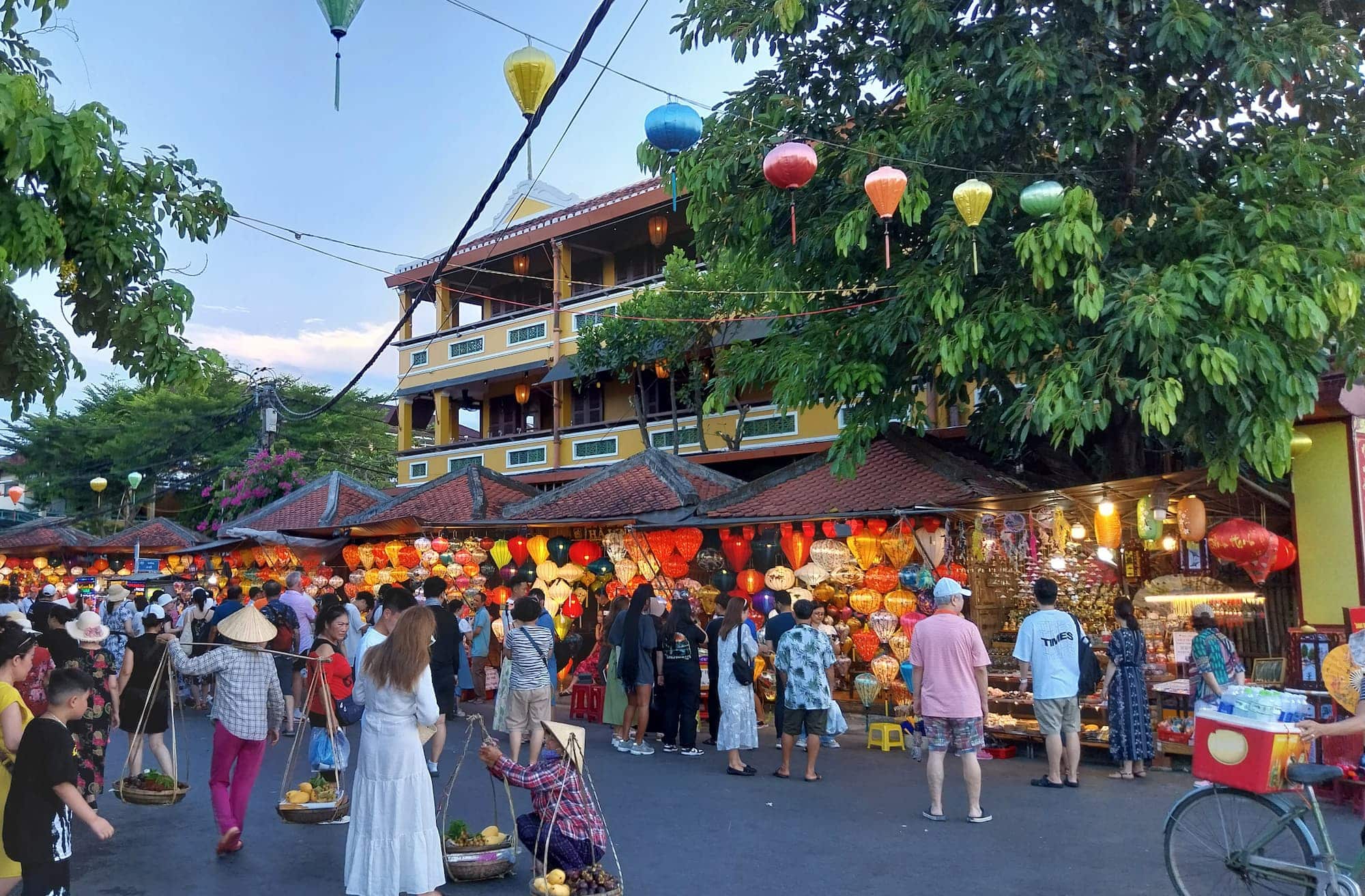 A crowded market with lanterns and people walking around.