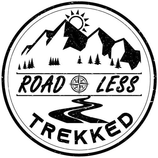 Black and white circular logo with mountains, trees, a winding road, compass, and the words "ROAD LESS TREKKED.